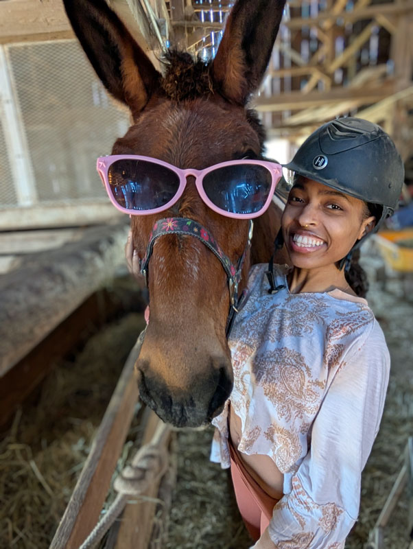 Smiling woman with mule wearing sunglasses.